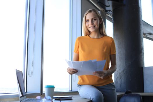 Beautiful smiling business woman is sitting in the office and looking at camera.