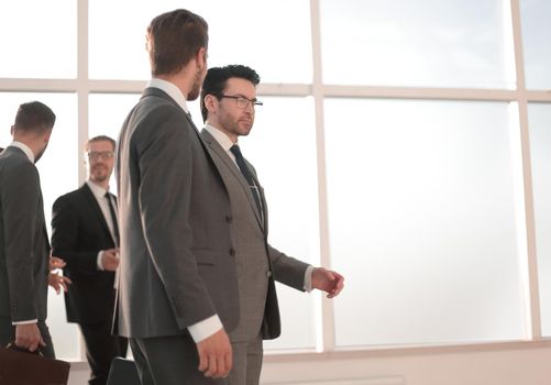 Confident businessman with colleagues strolling in the office