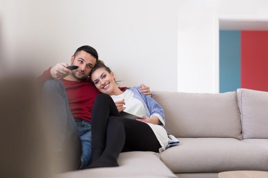 Young couple on the sofa watching television together in their luxury home