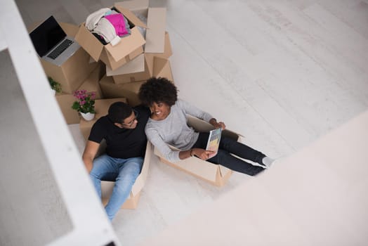 African American couple sitting in a box playing with packing material, having fun after moving in new home