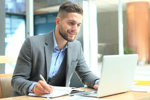 Portrait of young man sitting at his desk in the office