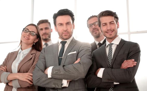 Team of successful happy businesspeople standing in office, businesswoman in front smiling.