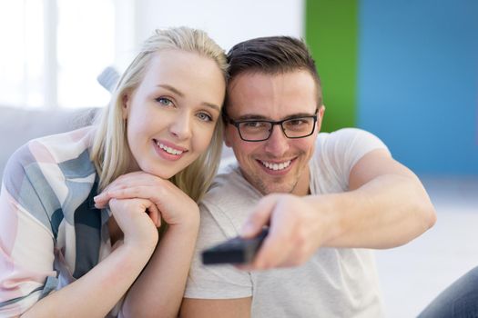 Young couple on the sofa watching television together in their luxury home