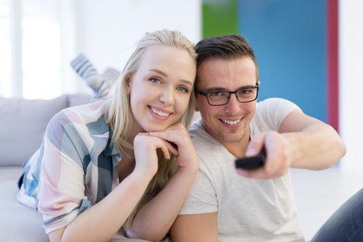 Young couple on the sofa watching television together in their luxury home