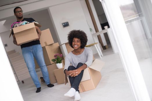 African American couple sitting in a box playing with packing material, having fun after moving in new home