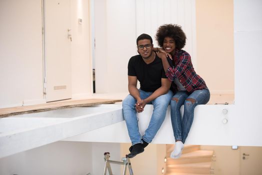 Happy young African American couple having break during moving to new house