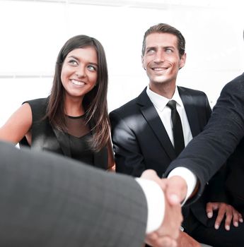 leader of the business team welcomes client shaking hands in office lobby.the concept of partnership.