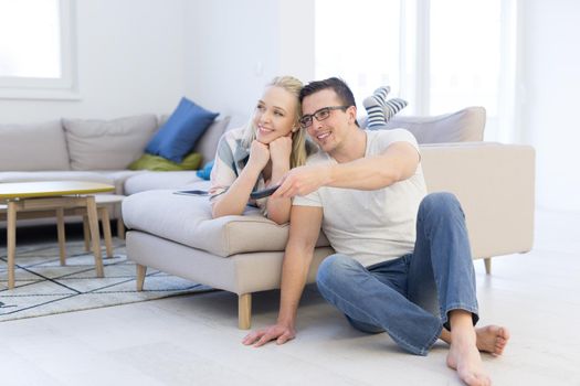 Young couple on the sofa watching television together in their luxury home