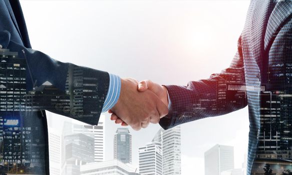 Close-up of the handshake of businessmen. Against the backdrop of the cityscape