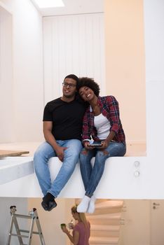 Happy young African American couple having break during moving to new house