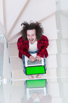 young freelancer in bathrobe working from home using laptop computer while sitting on stairs