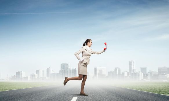 Woman running outdoor with vintage red phone. Expressive secretary with telephone on background downtown. Hotline telemarketing and communication. Professional business assistance and support