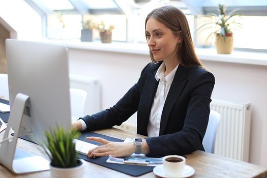 Portrait of a young blond business woman using computer at office