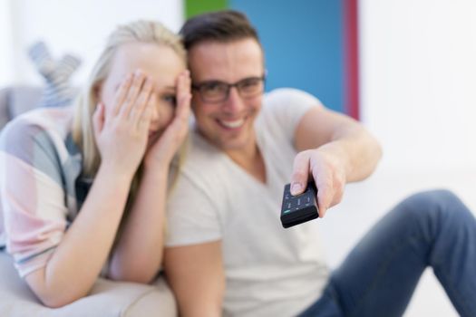 Young couple on the sofa watching television together in their luxury home