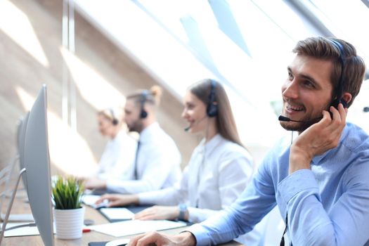 Portrait of call center worker accompanied by his team. Smiling customer support operator at work