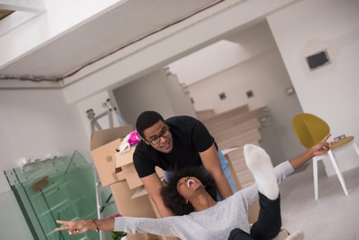 African American couple sitting in a box playing with packing material, having fun after moving in new home