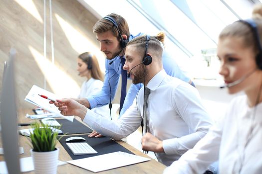 Phone operator working at call centre office helping his colleague