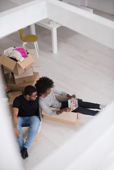 African American couple sitting in a box playing with packing material, having fun after moving in new home