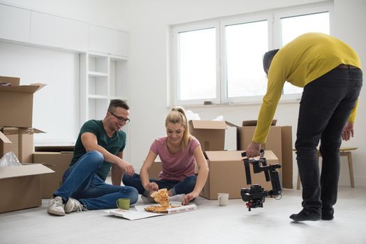 happy young couple have a pizza lunch break on the floor after moving into a new home with boxes around them