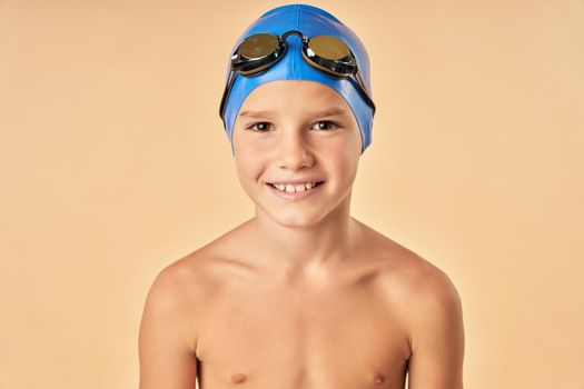 Close up of cute male child in swim cap looking at camera and smiling