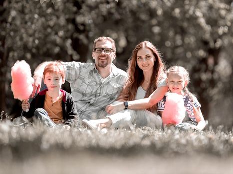 happy family sitting on the lawn in the city Park.the concept of family entertainment