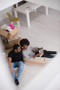 African American couple sitting in a box playing with packing material, having fun after moving in new home