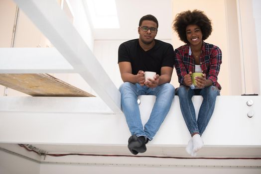 Happy young African American couple having break during moving to new house