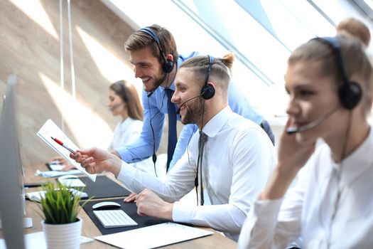 Phone operator working at call centre office helping his colleague