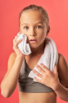 Close up of cute girl in crop top looking at camera with amazed expression while standing against red background