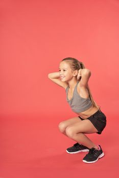 Adorable female child in sportswear looking away and smiling while doing exercise