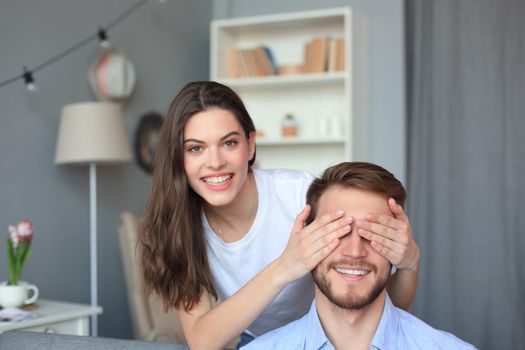 Young cute woman covering her husband's eyes