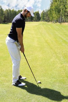 Full length of golf player playing golf on sunny day. Professional male golfer taking shot on golf course