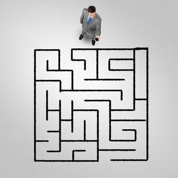 Top view of puzzled businessman looking at drawn maze on floor