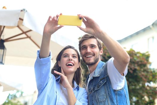 Beautiful lovely young couple walking at the city streets, taking a selfie