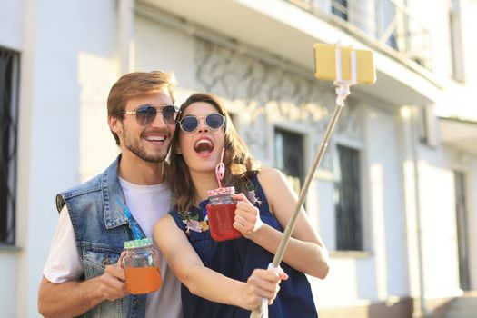 Beautiful lovely young couple walking at the city streets, hugging while taking a selfie