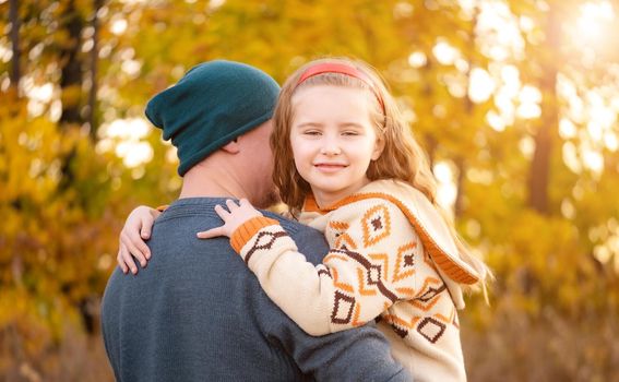 Father hugs with daughter on blurred autumn background