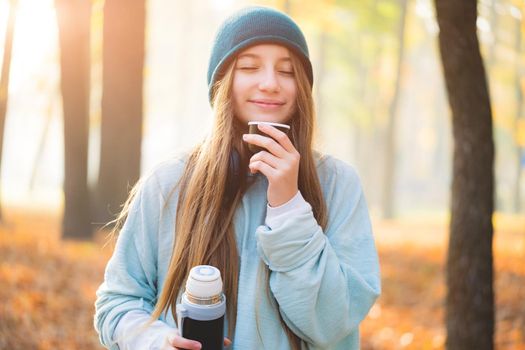 Lovely girl enjoying hot coffee on autumn background