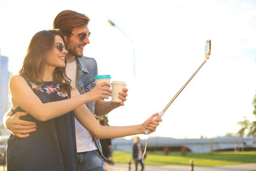 Beautiful lovely young couple walking at the city streets, hugging while taking a selfie