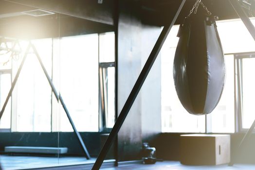 Boxing. Black punching bag in empty gym, selective focus. Sport and active lifestyle concept