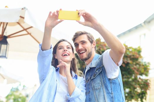 Beautiful lovely young couple walking at the city streets, hugging while taking a selfie