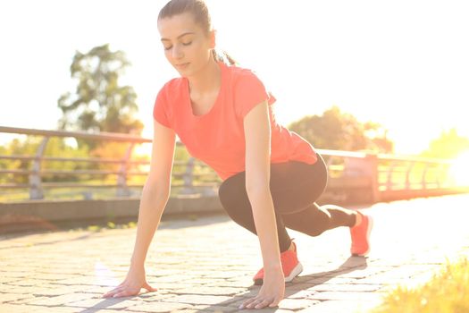 Beautiful young woman in sports clothing standing on the start line while running outdoors