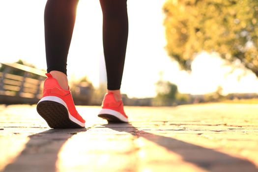 Runner feet running on road closeup on shoe, outdoor at sunset or sunrise