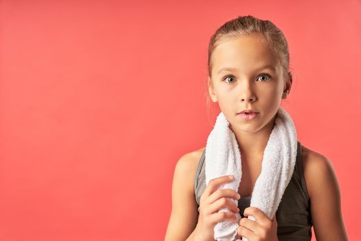 Adorable girl with towel around her neck looking at camera with astonished expression