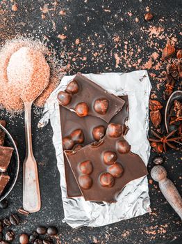 Chocolate with nuts and spices in the spoons on a dark table