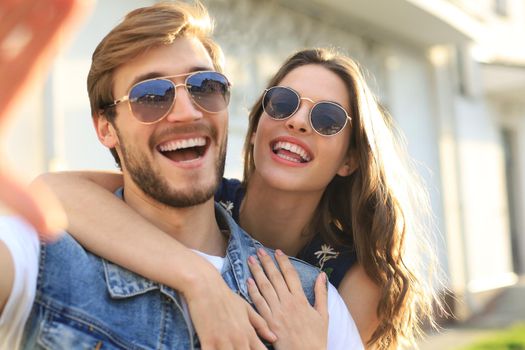 Beautiful lovely young couple walking at the city streets, hugging while taking a selfie