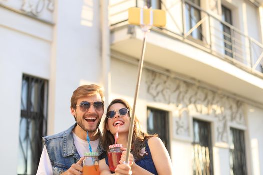 Beautiful lovely young couple walking at the city streets, hugging while taking a selfie