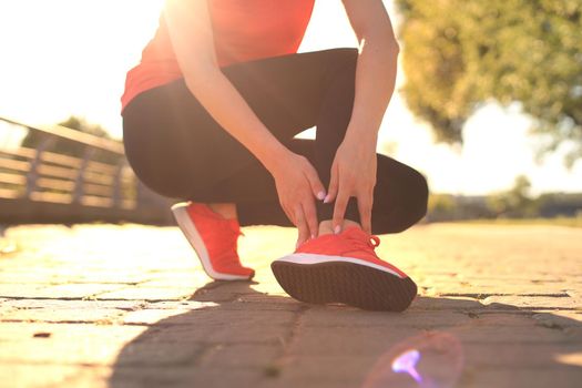 Sport woman - runner holding painful sprained ankle in pain. Female athlete with joint or muscle soreness and problem feeling ache in her lower body