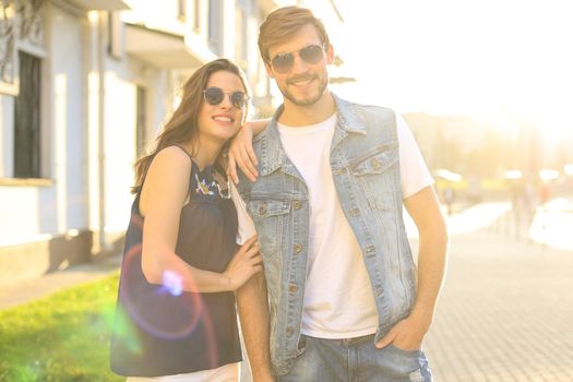 Image of lovely happy couple in summer clothes smiling and holding hands together while walking through city street