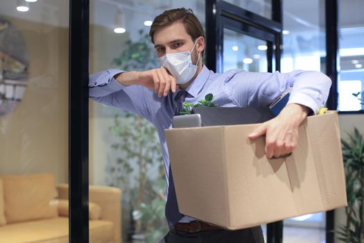 Dismissal employee in preventive medical mask in an epidemic coronavirus. Dismissed worker going from the office with his office supplies