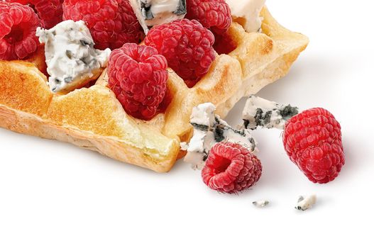 Closeup french waffles with raspberries and dorblu cheese. A few pieces of cheese and berries nearby. Isolated on white background